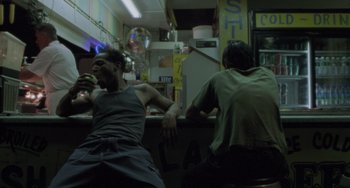 Movie still from “Requiem for a Dream” (2000), directed by Darren Aronofsky – Two men sitting at a bar drinking and eating food; Medium shot, Low angle