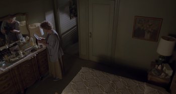Movie still from “Requiem for a Dream” (2000), directed by Darren Aronofsky – An older woman standing in a bedroom next to a bed; Wide shot, High angle