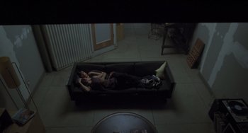 Movie still from “Requiem for a Dream” (2000), directed by Darren Aronofsky – Two people laying on a couch in a living room; Wide shot, Overhead angle
