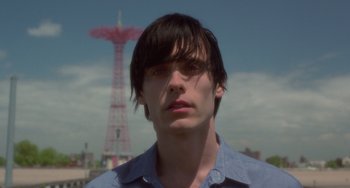 Movie still from “Requiem for a Dream” (2000), directed by Darren Aronofsky – A young man with long black hair wearing a blue shirt; Close Up shot, Low angle