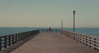 Movie still from “Requiem for a Dream” (2000), directed by Darren Aronofsky – A person sitting on a pier looking out at the ocean; Extreme Wide shot, High angle