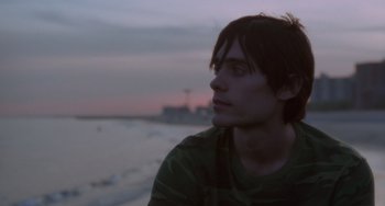 Movie still from “Requiem for a Dream” (2000), directed by Darren Aronofsky – A man sitting on the beach at sunset; Close Up shot, Over the shoulder angle