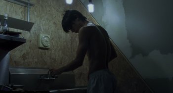 Movie still from “Requiem for a Dream” (2000), directed by Darren Aronofsky – A shirtless man washing his hands in a bathroom; Medium shot, Low angle