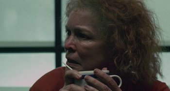 Movie still from “Requiem for a Dream” (2000), directed by Darren Aronofsky – An older woman is holding a cup in her hands; Close Up shot, Over the shoulder angle