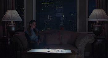 Movie still from “Requiem for a Dream” (2000), directed by Darren Aronofsky – A woman sitting on a couch in front of a window at night; Medium shot, High angle
