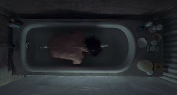 Movie still from “Requiem for a Dream” (2000), directed by Darren Aronofsky – A person in a bathtub with a hair brush; Wide shot, Overhead angle