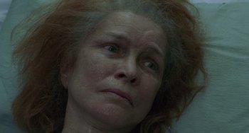 Movie still from “Requiem for a Dream” (2000), directed by Darren Aronofsky – An older woman with very long red hair looking at the camera; Close Up shot, Overhead angle
