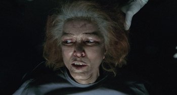 Movie still from “Requiem for a Dream” (2000), directed by Darren Aronofsky – An older woman with white hair is looking at the camera; Close Up shot, Overhead angle