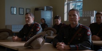 Movie still from “Rescued by Ruby” (2022), directed by Katt Shea – A group of men sitting at a table wearing hats; Medium shot, Over the shoulder angle
