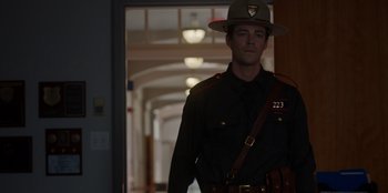 Movie still from “Rescued by Ruby” (2022), directed by Katt Shea – A man in a uniform is standing in a hallway; Medium shot, Over the shoulder angle