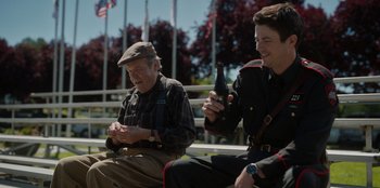 Movie still from “Rescued by Ruby” (2022), directed by Katt Shea – Two men sitting on a bench one is holding a bottle of wine and the other is holding a bottle; Medium shot, Over the shoulder angle