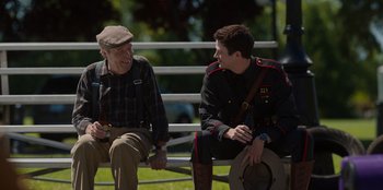Movie still from “Rescued by Ruby” (2022), directed by Katt Shea – Two men sitting on a park bench talking to each other; Medium shot, Over the shoulder angle