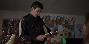 Movie still from “Rescued by Ruby” (2022), directed by Katt Shea – A man in a uniform is reading a book; Medium shot, Low angle