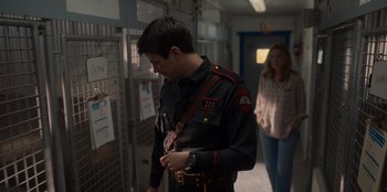 Movie still from “Rescued by Ruby” (2022), directed by Katt Shea – A man in a uniform is looking down at his watch; Medium shot, Over the shoulder angle