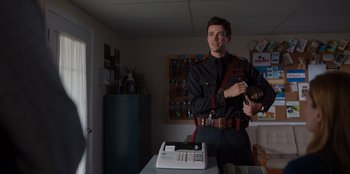 Movie still from “Rescued by Ruby” (2022), directed by Katt Shea – A man in uniform standing in front of a phone; Medium shot, Low angle