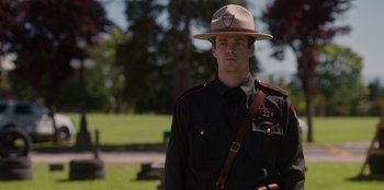 Movie still from “Rescued by Ruby” (2022), directed by Katt Shea – A man in a uniform is standing in a park; Close Up shot, Over the shoulder angle