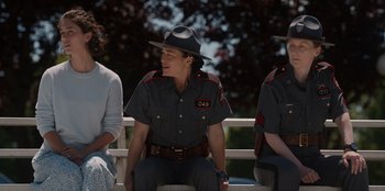 Movie still from “Rescued by Ruby” (2022), directed by Katt Shea – A man in a uniform sitting on a bench; Medium shot, Over the shoulder angle