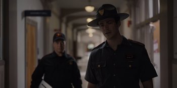 Movie still from “Rescued by Ruby” (2022), directed by Katt Shea – A man in a hat is standing next to another man in a uniform; Medium shot, Over the shoulder angle