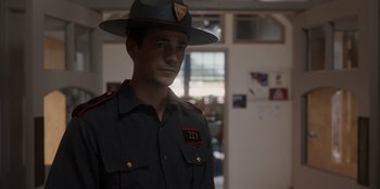 Movie still from “Rescued by Ruby” (2022), directed by Katt Shea – A man in a uniform is wearing a hat; Medium shot, Over the shoulder angle