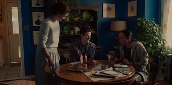 Movie still from “Rescued by Ruby” (2022), directed by Katt Shea – A group of people sitting around a table with a cake on it; Wide shot, Over the shoulder angle