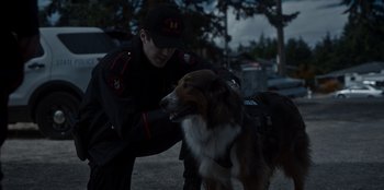 Movie still from “Rescued by Ruby” (2022), directed by Katt Shea – A police officer petting a dog on the street; Medium shot, Over the shoulder angle