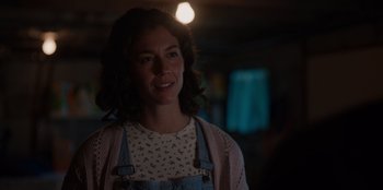 Movie still from “Rescued by Ruby” (2022), directed by Katt Shea – A young woman smiles for the camera in the dark; Close Up shot, Over the shoulder angle