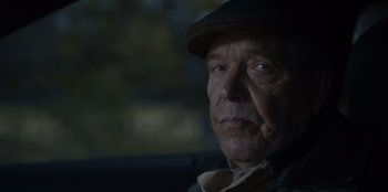 Movie still from “Rescued by Ruby” (2022), directed by Katt Shea – An older man wearing a hat looking at the camera; Close Up shot, Over the shoulder angle