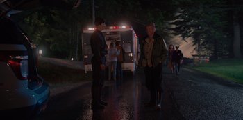 Movie still from “Rescued by Ruby” (2022), directed by Katt Shea – Two men standing on the side of the road near an ambulance; Wide shot, Over the shoulder angle