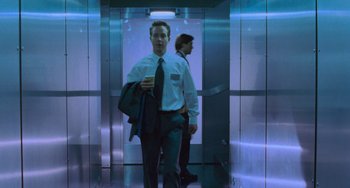 Movie still from “Resident Evil” (2002), directed by Paul W.S. Anderson – A man in a suit and tie standing in front of another man in a suit and tie; Medium shot, Low angle