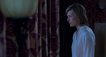 Movie still from “Resident Evil” (2002), directed by Paul W.S. Anderson – A woman standing in front of a curtain looking to her left; Medium shot, Low angle
