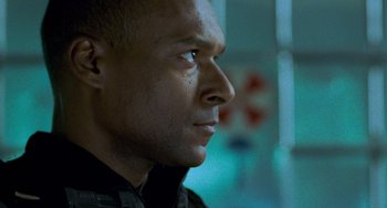 Movie still from “Resident Evil” (2002), directed by Paul W.S. Anderson – A man's face in a dark room; Close Up shot, Over the shoulder angle