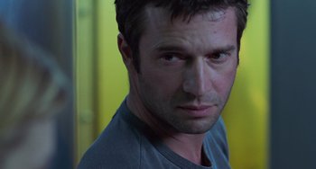 Movie still from “Resident Evil” (2002), directed by Paul W.S. Anderson – A person wearing a gray t - shirt; Close Up shot, Over the shoulder angle