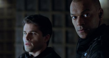 Movie still from “Resident Evil” (2002), directed by Paul W.S. Anderson – Two men are standing next to each other in a room; Close Up shot, Over the shoulder angle