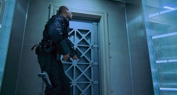 Movie still from “Resident Evil” (2002), directed by Paul W.S. Anderson – A man holding a gun while standing in front of an open door; Medium shot, Low angle