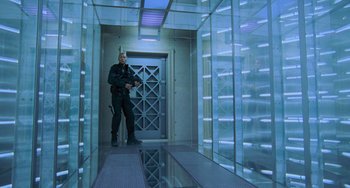Movie still from “Resident Evil” (2002), directed by Paul W.S. Anderson – A man standing inside of a room with a glass wall; Wide shot, Low angle