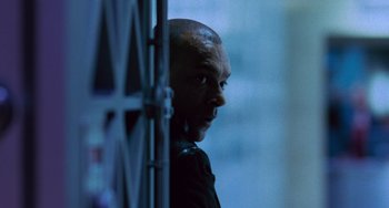 Movie still from “Resident Evil” (2002), directed by Paul W.S. Anderson – A man with a shaved head looking out of a window; Close Up shot, Low angle