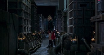 Movie still from “Resident Evil” (2002), directed by Paul W.S. Anderson – A woman standing in a room filled with stacks of books; Wide shot, Low angle