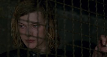 Movie still from “Resident Evil” (2002), directed by Paul W.S. Anderson – A woman looking out through a chain link fence; Close Up shot, Over the shoulder angle
