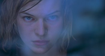 Movie still from “Resident Evil” (2002), directed by Paul W.S. Anderson – A woman's face with blue light coming from behind her; Close Up shot, Low angle