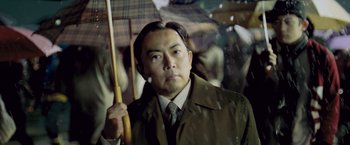 Movie still from “Resident Evil: Afterlife” (2010), directed by Paul W.S. Anderson – A man holding an umbrella while standing in the rain; Close Up shot, Low angle