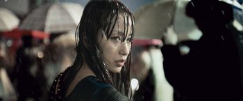 Movie still from “Resident Evil: Afterlife” (2010), directed by Paul W.S. Anderson – A young woman with wet hair holding an umbrella; Close Up shot, Low angle