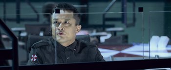 Movie still from “Resident Evil: Afterlife” (2010), directed by Paul W.S. Anderson – A man sitting at a desk in front of a window; Close Up shot, Low angle