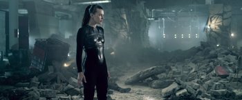 Movie still from “Resident Evil: Afterlife” (2010), directed by Paul W.S. Anderson – A woman in a black body suit standing in an abandoned building; Medium shot, Low angle