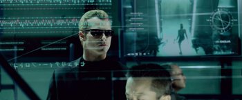 Movie still from “Resident Evil: Afterlife” (2010), directed by Paul W.S. Anderson – A man in a black shirt and a man with blonde hair and sunglasses; Close Up shot, Over the shoulder angle