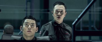 Movie still from “Resident Evil: Afterlife” (2010), directed by Paul W.S. Anderson – A man in a black shirt is talking to another man; Close Up shot, Over the shoulder angle