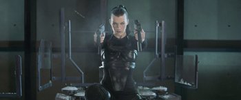 Movie still from “Resident Evil: Afterlife” (2010), directed by Paul W.S. Anderson – A woman holding two guns while wearing a black outfit; Medium shot, Low angle