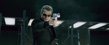 Movie still from “Resident Evil: Afterlife” (2010), directed by Paul W.S. Anderson – A man in sunglasses is holding a gun in his hand; Medium shot, Low angle