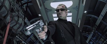 Movie still from “Resident Evil: Afterlife” (2010), directed by Paul W.S. Anderson – A man in a black suit holding a gun in his hand; Medium shot, Low angle