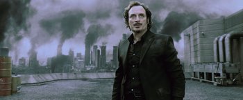 Movie still from “Resident Evil: Afterlife” (2010), directed by Paul W.S. Anderson – A man standing in front of a city with smoke coming out of it; Close Up shot, Low angle