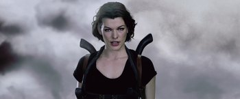 Movie still from “Resident Evil: Afterlife” (2010), directed by Paul W.S. Anderson – A woman in black shirt holding a pair of fake guns; Close Up shot, Over the shoulder angle